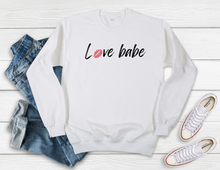 Load image into Gallery viewer, Softest Crewneck Sweatshirt. Designed to elevate your vibe to help you live your intention. We see you strive to surround yourself in love. You can consciously create your internal state when you practice living with love. Choosing peace, joy, compassion, gratitude and mindfulness, over and over and over, babe. Practice living with love, babe. For yourself and others, and radiate the loving human that you are. White crewneck sweatshirt with black love babe print and pink lips for the o in love.
